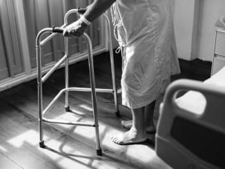 Crno bijela slika osobe oboljele od multiple skleroze s hodalicom.